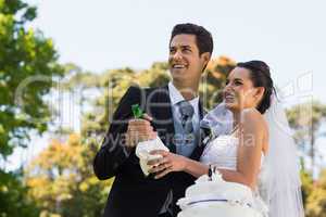 Newlywed couple with champagne bottle at park