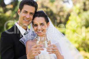 Newlywed toasting champagne flutes at park