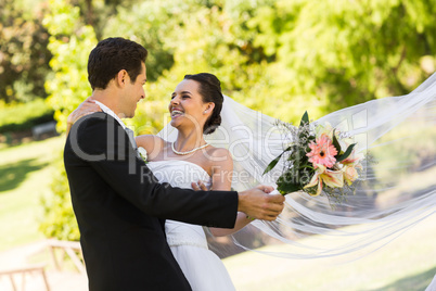 Cheerful newlywed couple dancing in park