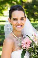 Close-up portrait of a beautiful bride with bouquet in park