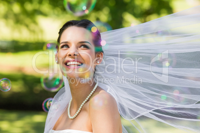 Beautiful bride looking at soap bubbles in park