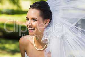 Cheerful young beautiful bride in park