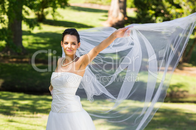 Smiling beautiful bride standing in park