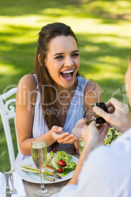 Man proposing cheerful woman at an outdoor cafÃ©