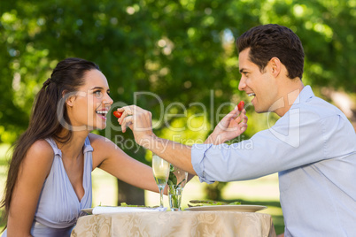 Couple feeding strawberries to each other at outdoor cafÃ&#