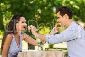 Couple feeding strawberries to each other at outdoor cafÃ&#