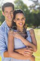 Smiling man embracing woman from behind at park