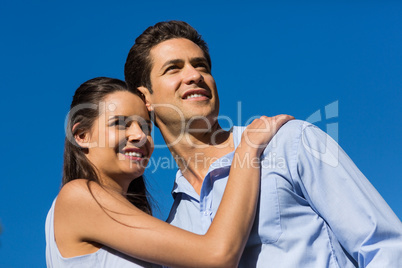 Young couple looking away against blue sky