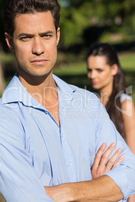 Man with blurred woman in background outdoors
