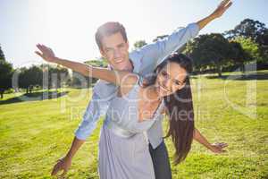 Happy couple with arms outstretched at park