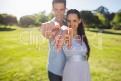 Young couple pointing finger to the camera at park