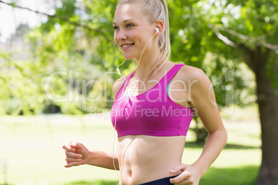 Healthy and beautiful young woman in sports bra jogging in park