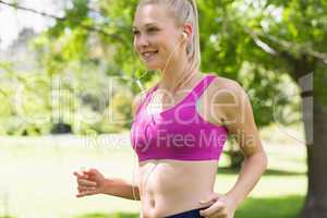 Healthy and beautiful young woman in sports bra jogging in park