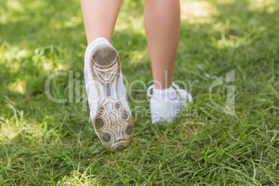 Low section of woman in sports shoes jogging at park