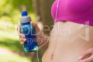 Mid section of healthy woman in sports bra with water bottle in