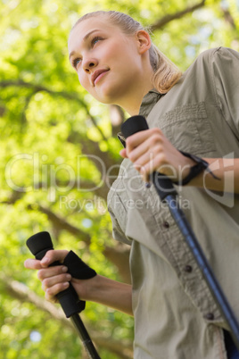 Beautiful young woman Nordic walking in park