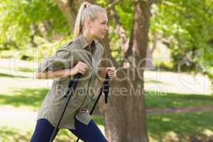 Beautiful young woman Nordic walking in park