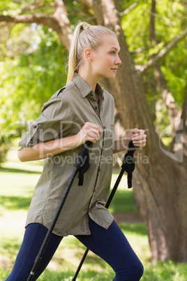 Beautiful young woman Nordic walking in park