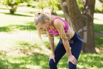 Tired woman in sports bra standing at park