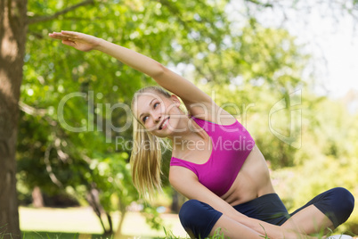 Healthy and beautiful woman doing stretching exercise in park