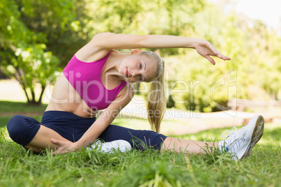Healthy and beautiful woman doing stretching exercise in park