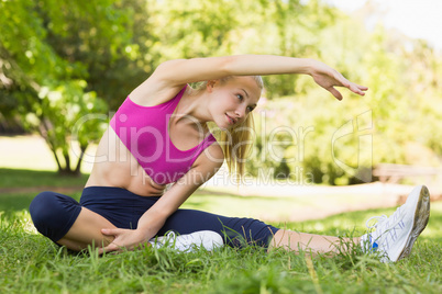 Healthy and beautiful woman doing stretching exercise in park