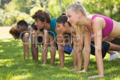 Group of fitness people doing push ups in park