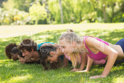 Group of fitness people doing push ups in park