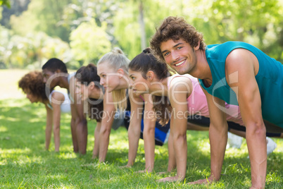 Group of fitness people doing push ups in park