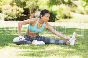 Healthy and beautiful woman stretching hand to leg in park