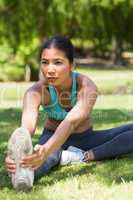 Healthy and beautiful woman stretching hands to leg in park