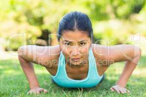 Portrait of a healthy woman doing push ups in park