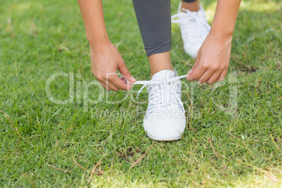Low section of woman tying shoe lace at park