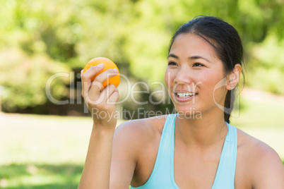 Close-up of woman holding orange in park