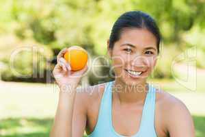 Healthy woman holding orange in park