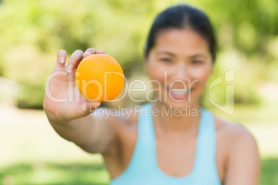 Healthy woman holding orange in park