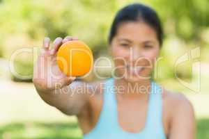 Healthy woman holding orange in park