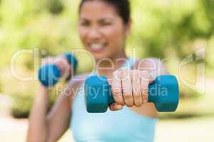 Blurred woman exercising with dumbbells in park