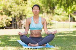 Sporty woman in lotus pose with eyes closed at park