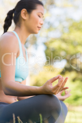 Sporty woman in lotus pose with eyes closed at park