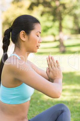 Sporty woman in Namaste position with eyes closed at park