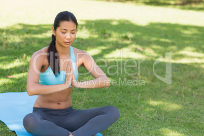 Woman in Namaste position with eyes closed at park