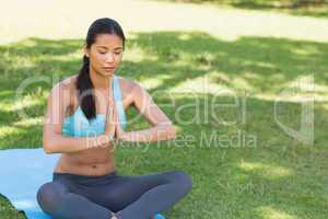 Woman in Namaste position with eyes closed at park