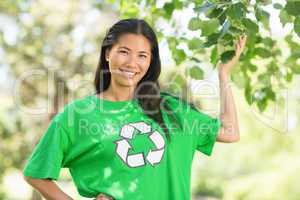 Woman in green recycling t-shirt touching leaves at park