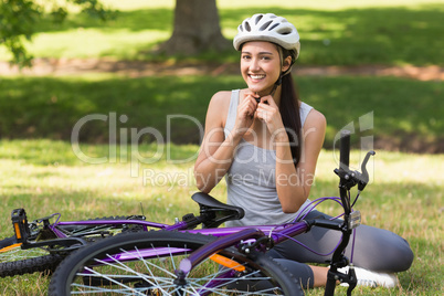 Cheerful woman wearing helmet besides bicycle in park