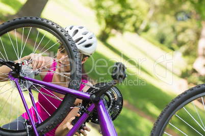 Woman trying to fix chain on mountain bike in park