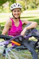Happy woman wearing helmet with bicycle in park