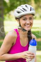 Fit woman in helmet holding water bottle at park