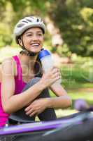 Fit woman in helmet holding water bottle at park