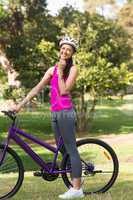 Fit woman with helmet and bicycle at park